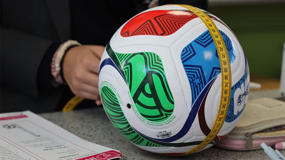 A football used in the World Cup being measured using a yellow measuring tape